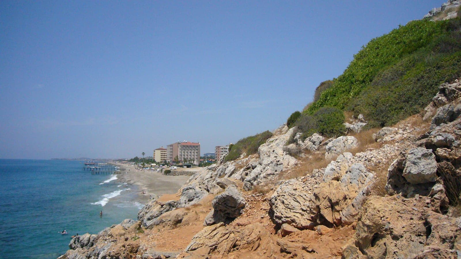 Wide sandy beach with swimmers and the town rising behind