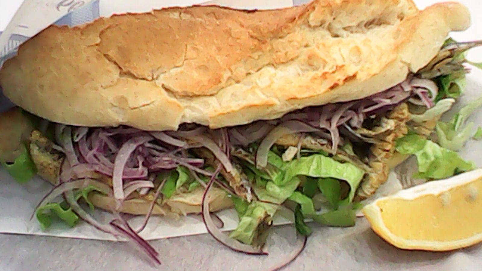 Fish sandwich served on a plate with salad
