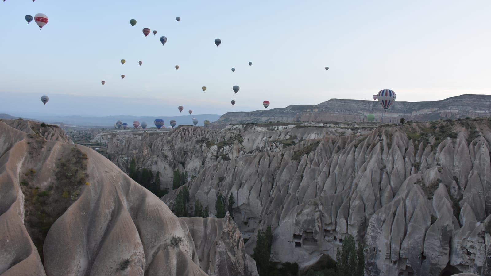 Balloons drifting low over the valleys just after sunrise
